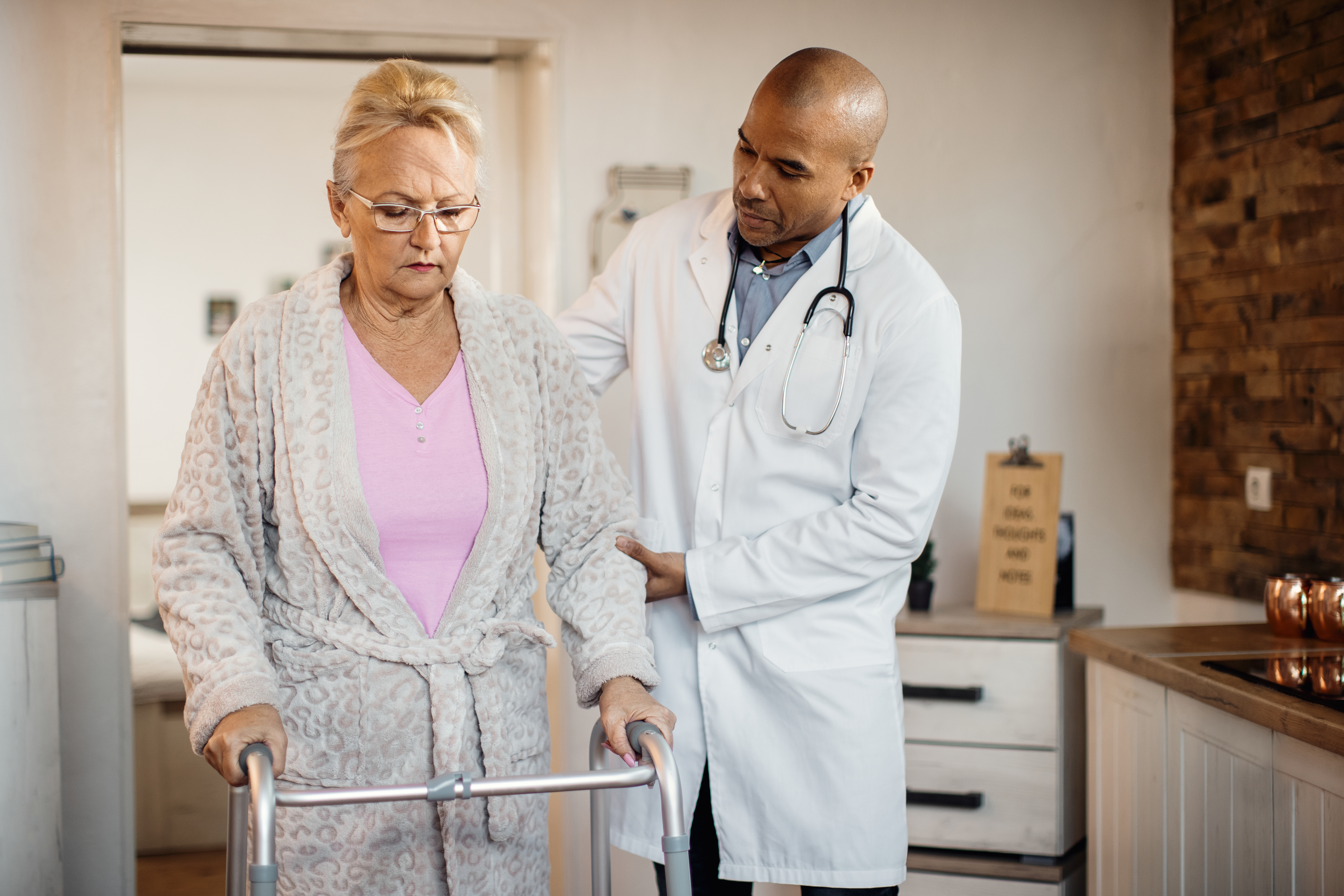 Physician helping an older woman use a walker at a nursing home