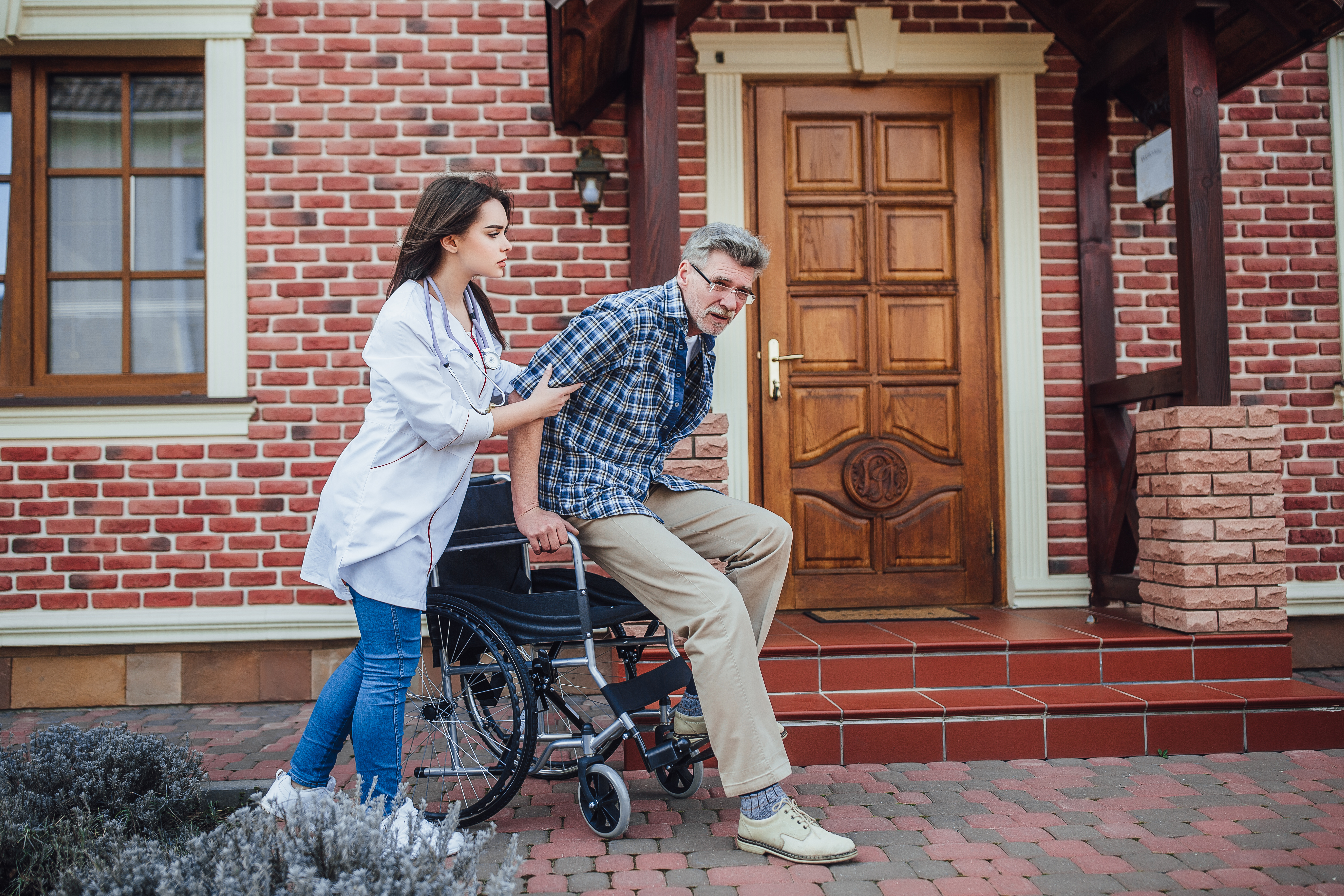 Nurse talking with an older man in a wheelchair in a nursing home garden