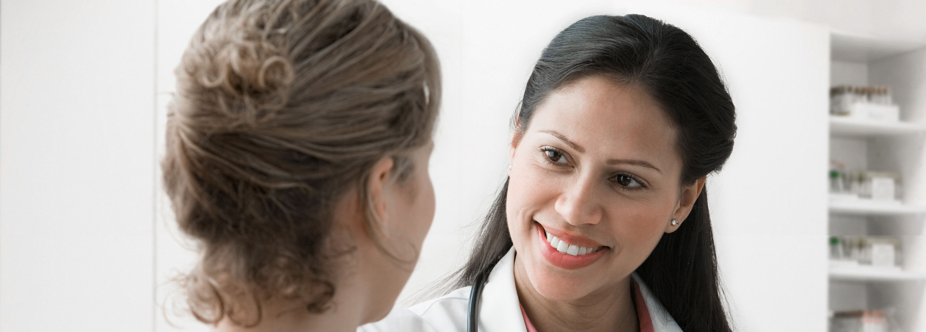 Physician smiling while speaking with a patient in an exam room