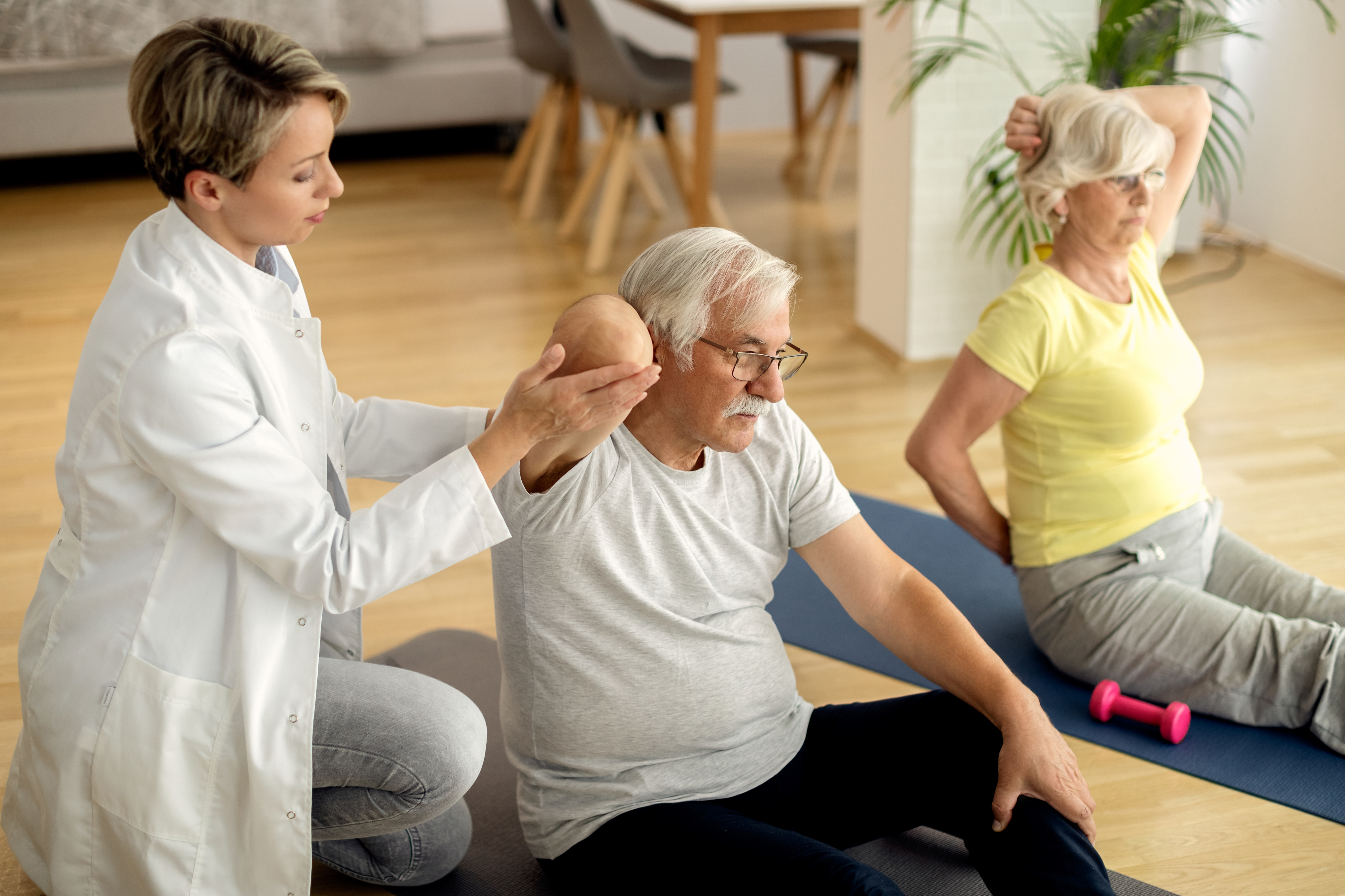 Physical therapist helping an older couple exercise at home